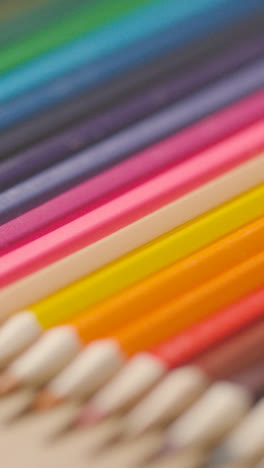 Vertical-Video-Of-Coloured-Pencils-Arranged-In-A-Line-On-Wooden-Background-1